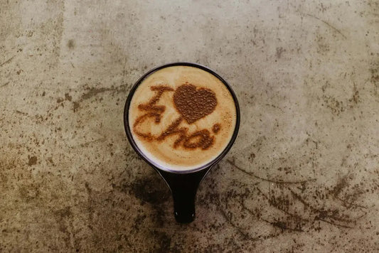 Gros plan dâune tasse fumante de chai latte aux Ă©pices, avec des bĂątons de cannelle, des noisettes et une mousse onctueuse, symbolisant la chaleur et le rĂ©confort dâun thĂ© chai maison.