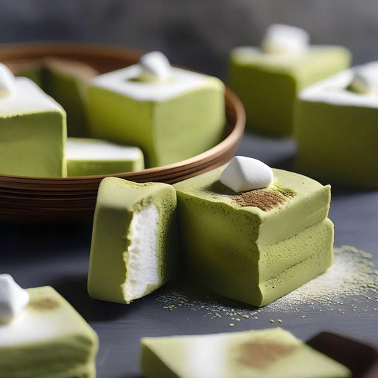 Guimauves moelleuses au matcha, saupoudrées de thé vert en poudre, posées sur une assiette claire, illustrant une douceur originale et gourmande aux notes végétales.