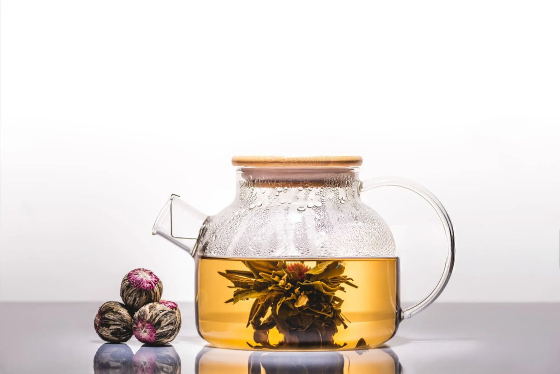 Théière avec fleur de thé éclose et trois bourgeons sur la table
