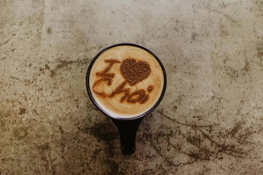 Gros plan d’une tasse fumante de chai latte aux épices, avec des bâtons de cannelle, des noisettes et une mousse onctueuse, symbolisant la chaleur et le réconfort d’un thé chai maison.