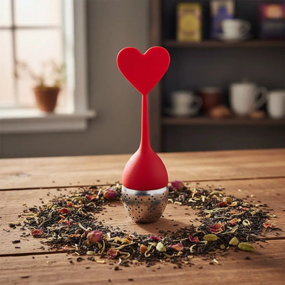 infuseur en silicone rouge en forme de coeur avec du thé en vrac autour 